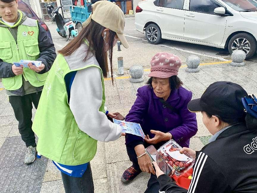 志愿者向西乡塘客运站周围行人宣传防范保健品诈骗的安全知识