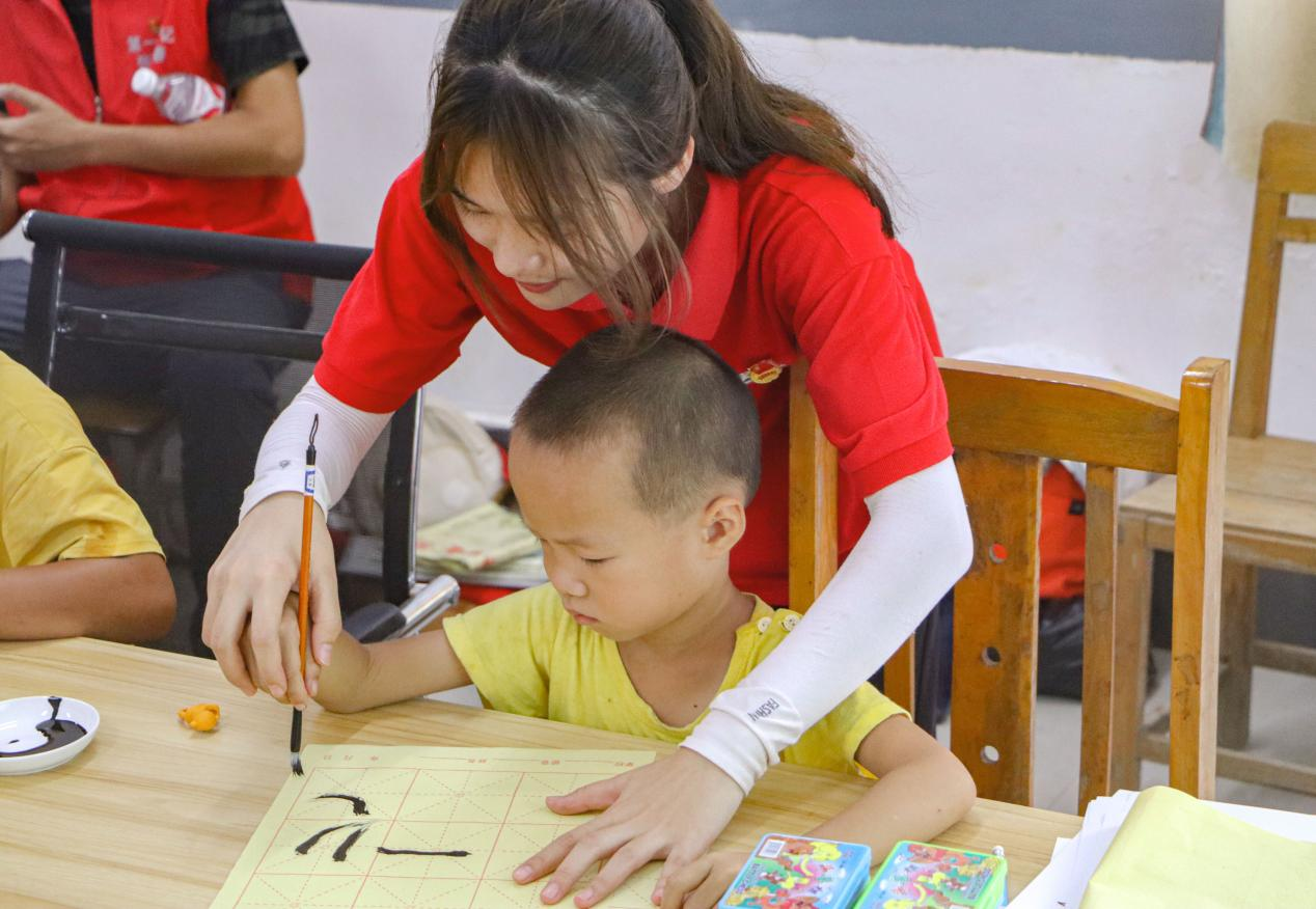 观察团成员指导小朋友书法